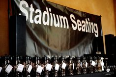 there are many bottles on the table with tags in front of them that say stadium seating