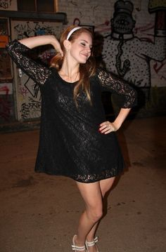 a young woman poses in front of graffiti covered walls