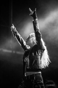 a woman with long hair holding her hands up in the air while performing on stage