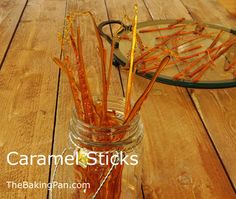 a jar filled with sticks sitting on top of a wooden table next to a glass plate