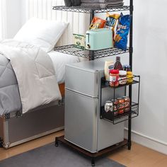 a bedroom with a bed, refrigerator and other items on the shelf next to it