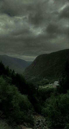 the sky is very dark and cloudy over some mountains