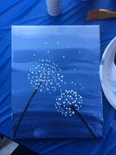 a blue painting with white dots on it next to a paper plate and paintbrush