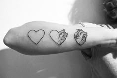 a woman's arm with three heart tattoos on it