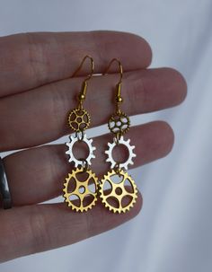 ♥ 10% off when you buy two pairs of earrings. Use code 10OFFTWO at checkout. ♥ Gold Silver Cog Gear Wheel Steampunk Earrings, Cog Gear Mech Earrings, Gold Cog Wheel Earrings, Steampunk Gear Earrings, Steampunk Cog Theme. Please see photo's for details. Earring length is 32 mm (3.2 cm / 1.25 inches) from bottom of hook. Made of 3 cogs, which start small and get larger as the earring descends. Smallest is 0.7 cm by 0.7 cm and the largest is 1.4 cm by 1.4 cm. A cute pair of earrings, made with gold toned ear hooks. These have silver toned and gold toned cog/gear charms. The first and last cogs are gold toned, the middle cog is silver toned.  A super cute quirky gift.  Posted recorded delivery.  Thanks for looking. Steampunk Earrings Diy, Gear Jewelry, Cog Wheel, Marvel Jewelry, Gear Earrings, Gear Wheels, Steampunk Earrings, Steam Punk Jewelry, Steampunk Gears