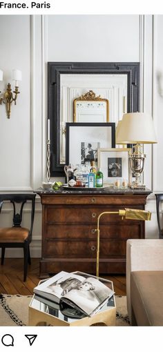 a living room filled with furniture and a lamp on top of a dresser next to a mirror