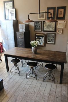 a dining room table with chairs and pictures on the wall