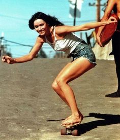 a woman is playing with a frisbee while another man looks on in the background