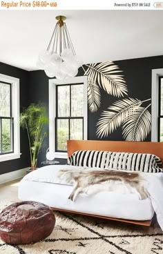 a bedroom with black walls and white bedding, large windows, an animal print rug on the floor