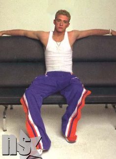 a man sitting on top of a couch next to a black sofa with orange and white pants