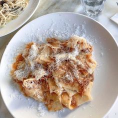 a white plate topped with pasta covered in parmesan cheese