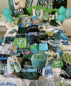 a bed covered in lots of green and white items with balloons on the headboard