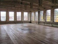 an empty room with wooden floors and large windows