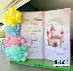 an open book with balloons in the shape of castle and rainbows on display at a children's birthday party