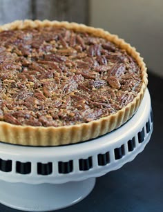 a pecan pie sitting on top of a white cake plate