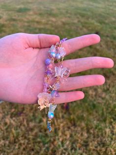 a person's hand holding several bracelets in the grass