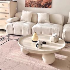 a living room with white couches and a coffee table in front of a painting on the wall