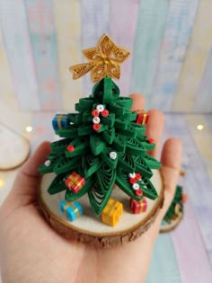 a hand holding a small christmas tree on top of a piece of wood