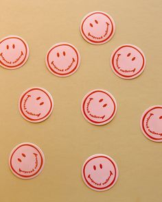 six red smiley face stickers sitting on top of a yellow tablecloth covered surface