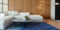 a modern living room with white furniture and wood paneling on the wall behind it