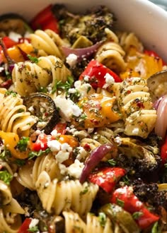 a bowl filled with pasta, vegetables and feta cheese