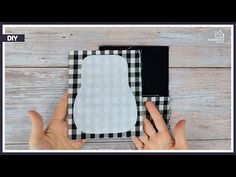 two hands are holding up a piece of paper that has been folded in half and is sitting on a wooden surface