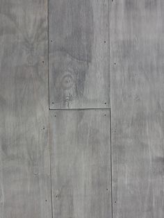 a cat laying on top of a wooden floor next to a white wall with holes in it