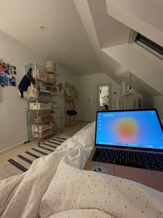 an open laptop computer sitting on top of a bed in a room with white walls