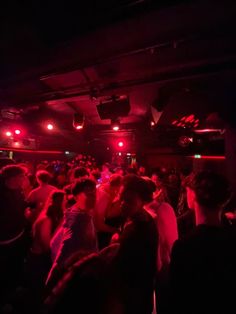 a group of people in a dark room with red lights on the ceiling and floor