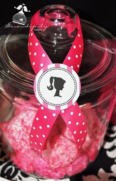 a jar filled with pink and white candies on top of a black table cloth