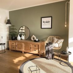 a living room filled with furniture and a mirror on top of a wooden dresser next to a window