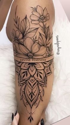 a woman's thigh with flowers on it and the words divine feminine written in black ink