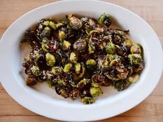 a white bowl filled with brussel sprouts on top of a wooden table