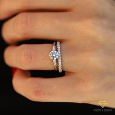 a woman's hand with a diamond ring on top of her finger and an engagement band