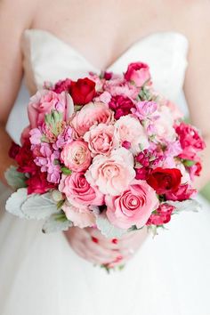 a bride holding a bouquet of pink and red flowers