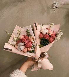 a person holding two bouquets of flowers in their hands, one pink and the other white