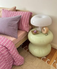 a bed with pink and white pillows on top of it next to a green table