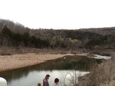 three people are standing in the water looking at something on the other side of the river