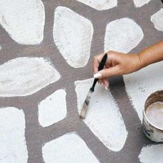 a person is using a brush to paint the floor with white and gray circles on it