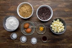 ingredients for chocolate chip cookies laid out in bowls on a wooden table with eggs and flour