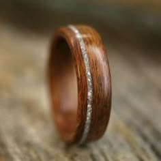 a wooden ring with gold inlays sits on a piece of wood, ready to be worn