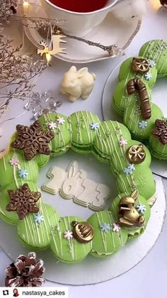 two cookies decorated like wreaths sitting on top of a table next to a cup of tea