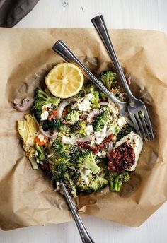 a plate with broccoli, cauliflower and lemon wedges