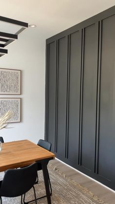 a dining room table with black chairs and art on the wall in the backround