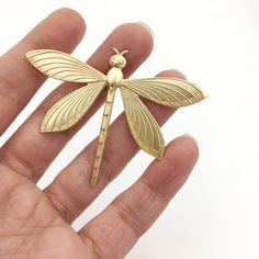 a small gold dragonfly brooch sitting on top of a person's hand