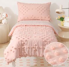 a bed with pink comforter and pillows on it in a room next to a lamp