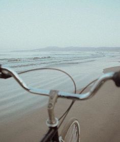 a bicycle is parked on the beach near the water