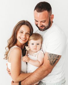 a man and woman holding a baby in their arms