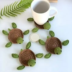 crocheted sea turtle coasters next to a coffee cup and fern leaf on a white table