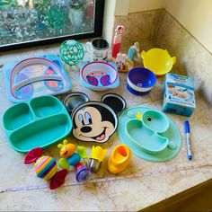 various mickey mouse dishes and toys on a counter